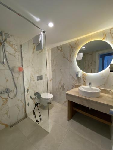 a bathroom with a shower and a sink and a mirror at Finike Marina Hotel in Finike