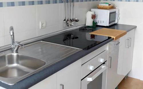 um balcão de cozinha com um lavatório e um micro-ondas em Apartamento renovado y tranquilo, ideal familias - los mejores accesos em Málaga