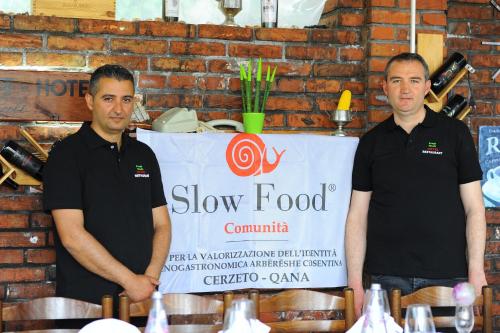 two men standing in front of a slow food sign at "Frogs House" Hotel & Restorant Slow Food in Lushnjë