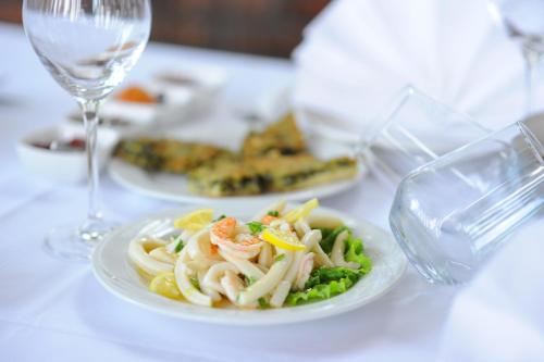a white plate of pasta and vegetables on a table at "Frogs House" Hotel & Restorant Slow Food in Lushnjë