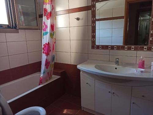 a bathroom with a sink and a shower curtain at Flamiatos Garden Cottages in Pouláta