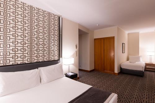 a hotel room with a bed and a bed and a bed and a bed at Hotel Mundial in Lisbon
