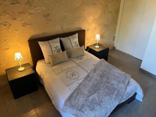 ein Schlafzimmer mit einem großen Bett mit zwei Nachttischen in der Unterkunft Gîte l'ombrière in Saint-Caprais-de-Bordeaux