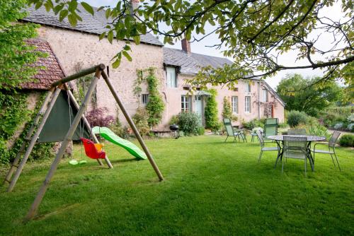 a playground with a table and chairs in a yard at Maison de vacances Les Mésanges, à Ménessaire in Ménessaire