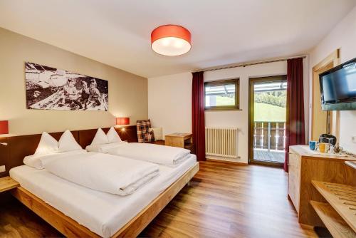a bedroom with a large bed and a flat screen tv at Garni Apparthotel St Valentin in San Valentino alla Muta