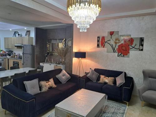 uma sala de estar com dois sofás e um lustre em Magnifique villa avec piscine privée dans une résidence sécurisée em Sidi Rahal