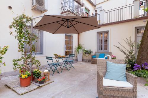 un patio con sombrilla, sillas y mesa en Il Cortile di Elisa & our flats, en Lucca