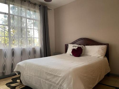 a bedroom with a bed with white sheets and a window at Cosy, serene and affordable 2bdr apartment off Waiyaki way in Nairobi