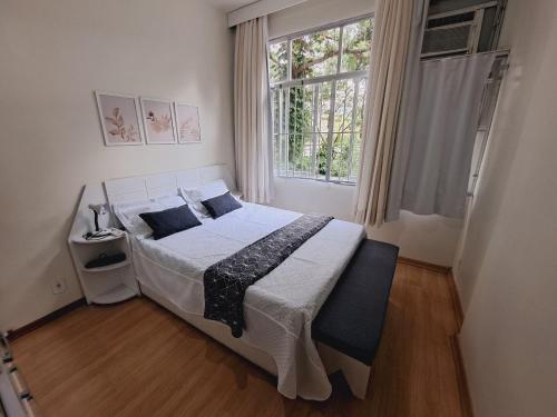 a bedroom with a large bed with a window at Apto Completo com VAGA entre Botafogo e Copacabana in Rio de Janeiro