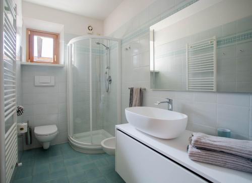 a white bathroom with a sink and a shower at Villetta al lago in Nago-Torbole
