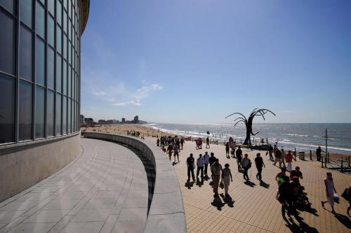 a group of people walking on a sidewalk near the beach at SeaCityView Oostende in Ostend