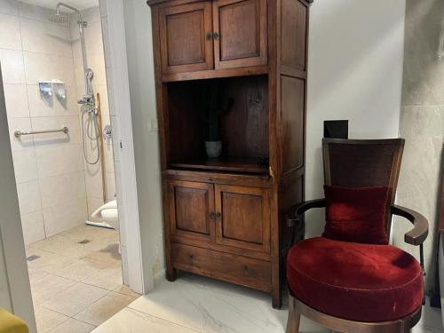 ein Badezimmer mit einem Holzschrank und einem roten Stuhl in der Unterkunft Ahuzat Shaul Seaside in H̱adera