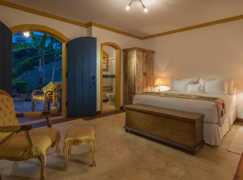 a bedroom with a bed and a chair and a window at Confraria Colonial Hotel Boutique in Mairinque