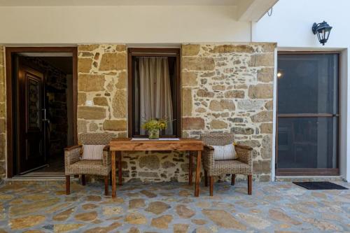 a table and two chairs in front of a stone wall at Apartments Panethimos 