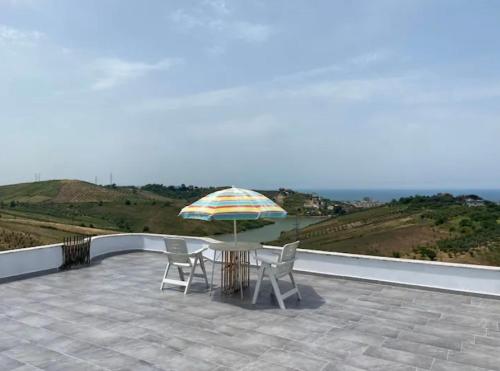 a patio with a table and chairs and an umbrella at Qerana's rooms: Corner of nature in Golem