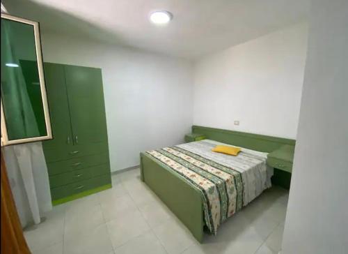 a bedroom with a bed with green cabinets and a mirror at Qerana's rooms: Corner of nature in Golem