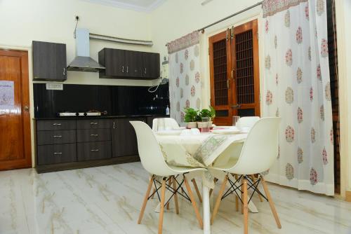 a dining room with a white table and white chairs at RAATREE in Mysore