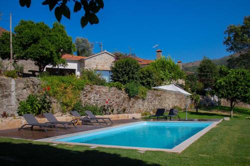 a swimming pool with chairs and a house at Quinta do Tapadinho - Wine & Tourism in Moimenta