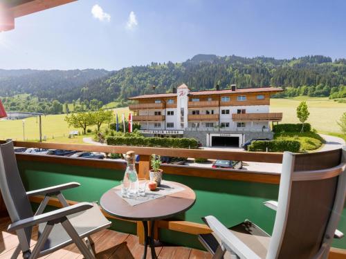 einen Balkon mit einem Tisch und Stühlen sowie ein Gebäude in der Unterkunft Hotel & Alpin Lodge Der Wastlhof in Niederau