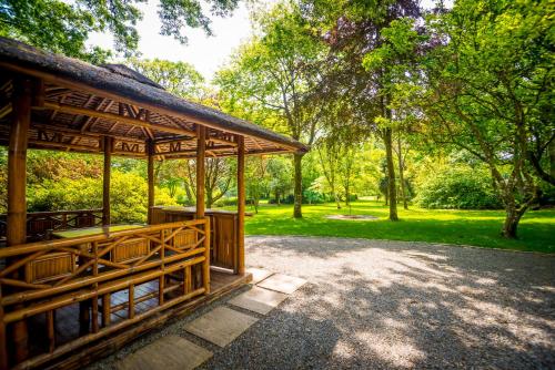 a pavilion in a park with trees and grass at Pinetum Garden Cottages in St Austell