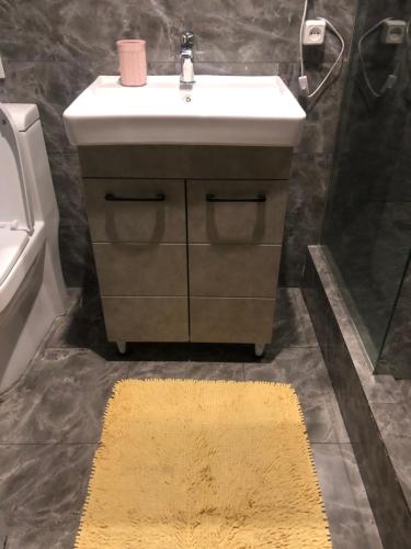 y baño con lavabo, espejo y alfombra. en Уютная квартира в центре города en Almaty