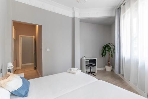 ein weißes Schlafzimmer mit einem Bett und einer Topfpflanze in der Unterkunft Piso reformado en Bilbao centro in Bilbao