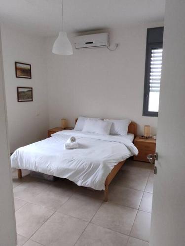 a bedroom with a white bed and a window at Desert View Home in Ashalim