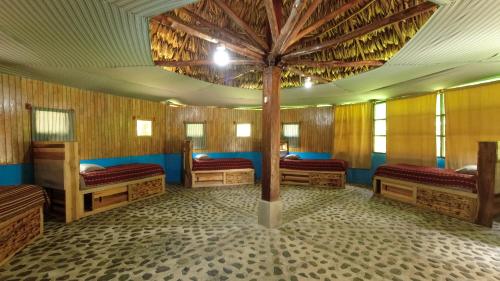 a room with four beds and a tree in the middle at El Retiro Lanquin in Lanquín