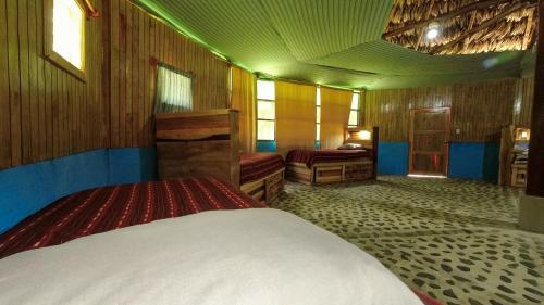 a bedroom with two beds in a room with wooden walls at El Retiro Lanquin in Lanquín