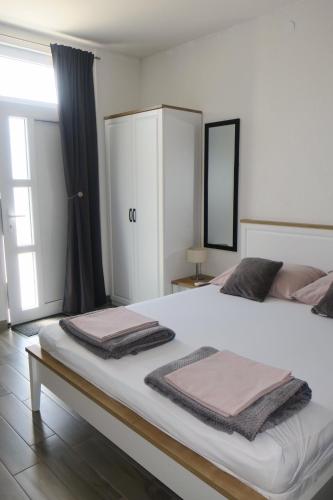 a large white bed with two folded towels on it at Mesić Apartment in Senj