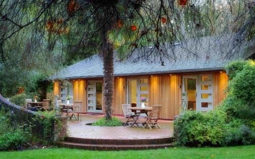 a house with a patio with a table and chairs at Pinetum Garden Cottages in St Austell