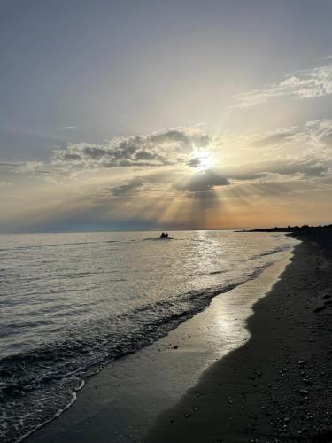 a beach with the sun setting in the ocean at B&BUrszula Gizzeria Lido in SantʼEufemia Lamezia