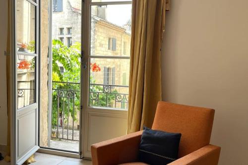 an orange chair sitting in front of a window at Uzès Centre Quartiers des Arts Charme de l'ancien in Uzès