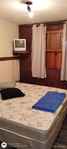 1 dormitorio con 1 cama grande y TV en la pared en Condomínio Alto da Boa Vista, en Campos do Jordão