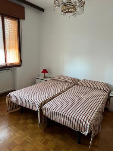 een slaapkamer met 2 bedden met gestreepte lakens en een kroonluchter bij Casa Gazzola in Crespano del Grappa
