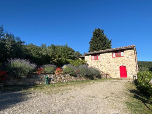 a stone house with a red door in a garden at Il Fiorino di Badia in Badia A Passignano