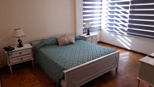 1 dormitorio con 1 cama, 2 mesitas de noche y ventana en El rincon de los Abuelos en Cochabamba