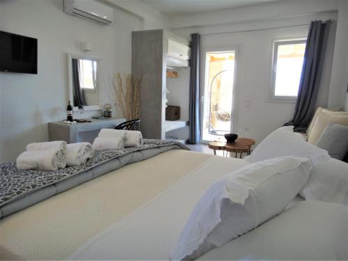 biała sypialnia z dużym białym łóżkiem z poduszkami w obiekcie Megusta Mykonos w mieście Tourlos