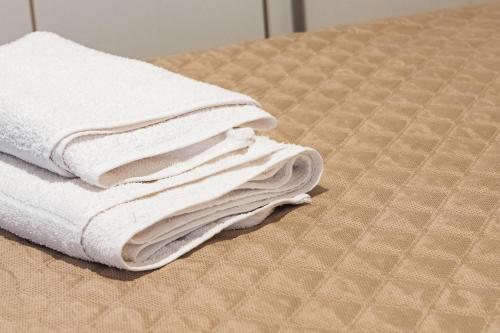 einen Stapel weißer Handtücher auf einem Bett in der Unterkunft Appartamento in pieno Centro Storico con terrazzo “O’vicariello” in Neapel