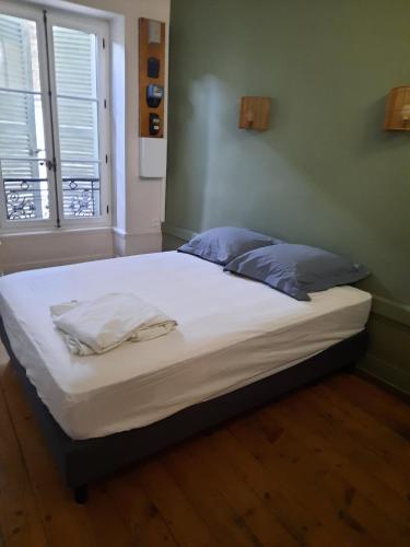 a bed with white sheets and blue pillows in a room at Le Cassandre in Givry