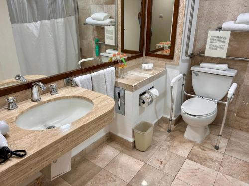a bathroom with a sink and a toilet and a mirror at Holiday Inn Merida, an IHG Hotel in Mérida