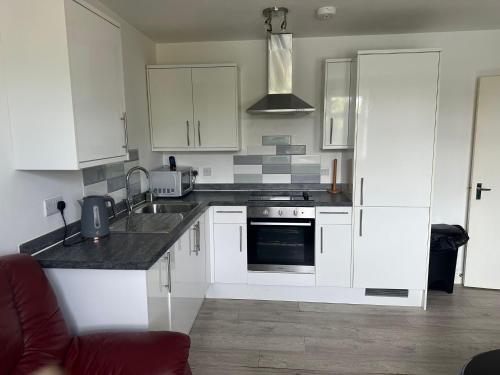 a kitchen with white cabinets and a stove top oven at Lovely 2 bedroom Flat at Palm Court in Bournemouth,5 minutes away from beach, whole flat is yours for the time you stayed in Bournemouth