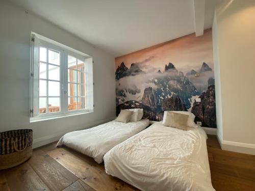 twee bedden in een slaapkamer met een schilderij aan de muur bij Loft Cathédrale in Bayonne