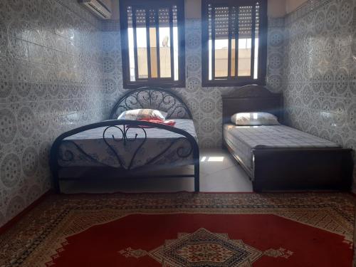 a bedroom with two beds and a rug and windows at Zitouna Rooms in Casablanca