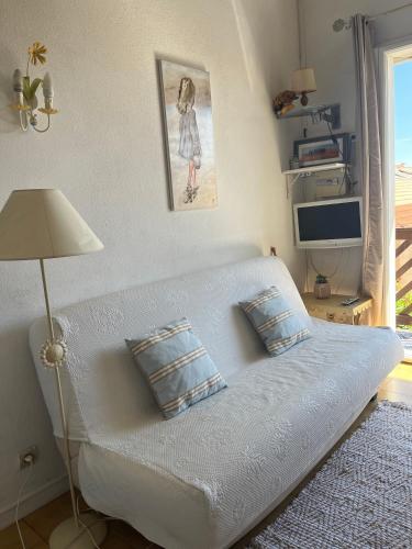 - un canapé blanc dans le salon doté d'une fenêtre dans l'établissement Le petit Baigneur de la grand bleue, à Port-Leucate
