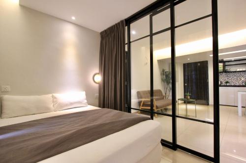 a bedroom with a large bed and a living room at Lovage Stay Melaka in Malacca