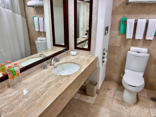 a bathroom with a sink and a toilet and a mirror at Holiday Inn Merida, an IHG Hotel in Mérida