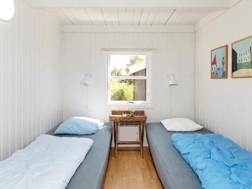 two beds in a room with a window at Four-Bedroom Holiday home in Fjerritslev 3 in Torup Strand