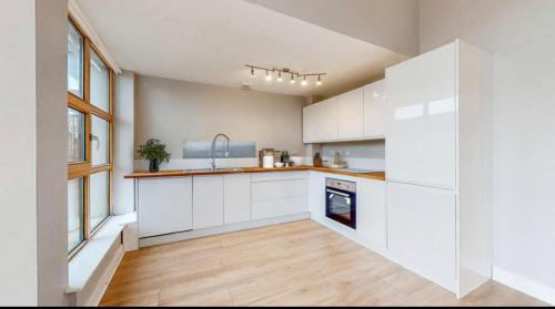 an empty kitchen with white cabinets and a wooden floor at Stylish Ensuite in Maryhill in Maryhill