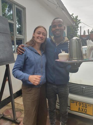 a man and a woman holding a tray with a pot at Meleji Studio House in Arusha